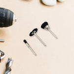 Three black nylon brushes with silver shafts are arranged on a light brown surface next to a drill and other tools.