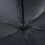The underside of the black umbrella reveals its metal frame and ribs, supporting the dark fabric canopy.