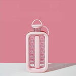 A pink ice ball maker bottle with clear sections containing ice spheres, set against a solid pink background.