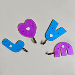Love shape self adhesive hooks in white, mounted on a wall.