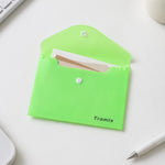 An open neon green plastic document folder with a white button closure and the word "Tramix" on it, containing small papers