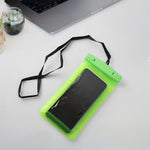 A green clear phone pouch with a black smartphone and lanyard sits on a white desk with a silver laptop and small potted