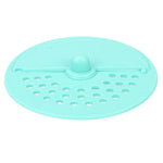 A light green silicone drain strainer with a central knob and two sections of holes is shown from above.