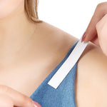 A person adheres a white strip of tape to the blue strap of a garment on their shoulder.