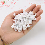 A hand holding a pile of white plastic cable clips with nails.
