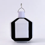 Compact white and black foldable LED lantern with a metal hook on a plain white background.