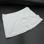 A white layered hip skirt with shorts lies folded on a dark gray surface.