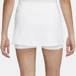 A woman models a white layered hip skirt with shorts and dark blue slip-on shoes, showing the back view.
