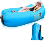 A woman in a white hat rests on a blue inflatable lounger with a phone in its side pocket, next to a blue carry bag.