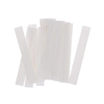 A pile of many thin, white, rectangular adhesive strips are scattered on a white background.