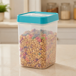 A clear plastic food storage container with a teal lid, filled with colorful cereal, sits on a kitchen counter.