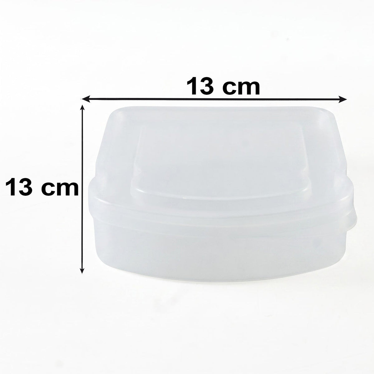 A clear plastic sandwich container with its lid is on a striped cloth on a wooden table with fruit and vegetables.