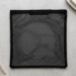 A flat black mesh zipper storage bag is laid out on a light grey textured surface.