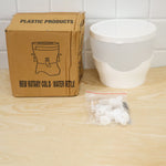 A cardboard box labeled "PLASTIC PRODUCTS NEW ROTARY COLD WATER KETTLE" sits next to the disassembled white plastic beverage