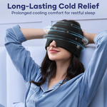 A woman in blue pajamas wearing a black migraine relief cap with blue cooling effects around her head.