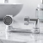 A close-up of the chrome swivel faucet aerator with water droplets on a white marble countertop.