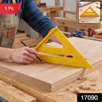 A person in a brown apron uses a yellow plastic speed square and pencil to mark a piece of light wood.