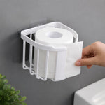 A hand tears a sheet from a roll of toilet paper held in a white plastic holder mounted on a gray wall.