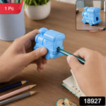 A light blue train-shaped double-hole pencil sharpener with a green pencil being sharpened, on a wooden desk with pencils.