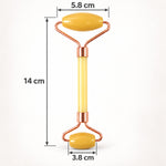 A yellow jade facial roller with rose gold frame is displayed with its dimensions of 14 cm length and roller widths of 5.8