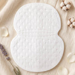 A single white, textured sweat pad on a light fabric background, surrounded by cotton bolls and lavender sprigs.