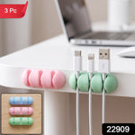 A pink and a green silicone cable organizer are attached to a white desk, holding three charging cables, with a '3 Pc' label