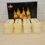 Twelve unlit, cream-colored, ribbed, hourglass-shaped LED candles are displayed in a clear plastic tray in front of their