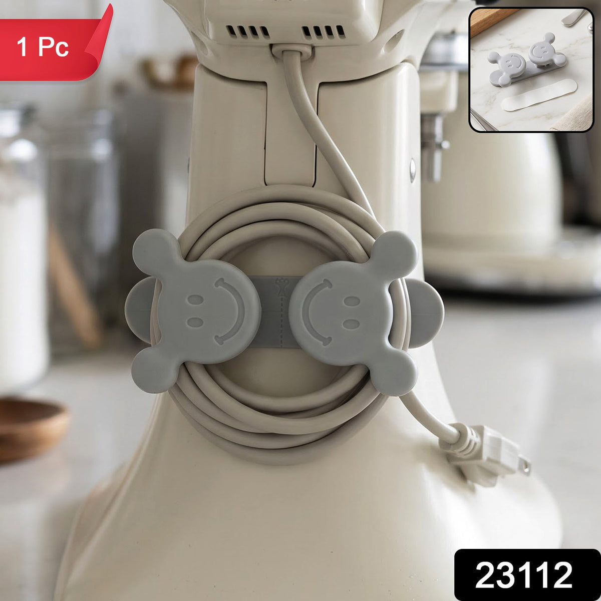 A gray silicone cord organizer with two smiling faces, holding a coiled light gray appliance cord on a white stand mixer,