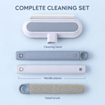 The cleaning set disassembled, showing the head, two handle pieces, and a separate detail brush on a blue surface.