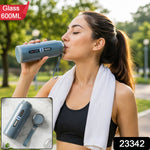 A woman in athletic wear drinks from a blue insulated bottle with a white towel around her neck outdoors. – view 2