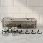 A clear grey plastic caddy, two silver suction cups, and four grey hooks are arranged on a white marble surface.