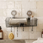 A clear grey plastic caddy with four hooks is mounted on a textured white wall, holding a sponge, keys, and a small bottle.