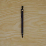 A blue mechanical pencil with a black tip and clip is centered on a light wooden surface.