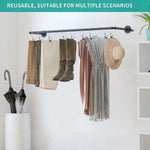 Multiple metal clip hangers are suspended from a black rod, holding various clothing items like pants, boots, a dress, and a