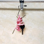 A close-up of a single metal clip hanger with a black rubber tip hangs from a silver rod, holding a coiled pink and white