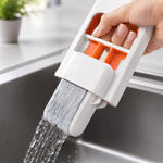 A hand uses the white and orange mini sponge mop to clean a window with suds, showing a blurred outdoor background.