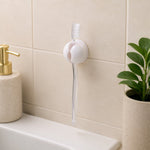 A white toothbrush holder clip on a tiled wall, holding a clear toothbrush above a sink, with a soap dispenser and – view 8