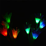 Several solar flower lights glow in various colors like red, orange, green, and blue in a dark setting.