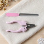 Pink pet nail clipper and filer on a light-colored linen cloth next to small white paw prints.