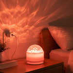 A white LED projection light on a bedside table, projecting red wavy patterns onto the wall and ceiling.