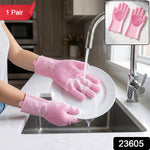Hands wearing pink silicone gloves with scrubbing bristles washing a white plate under running water in a kitchen sink, with