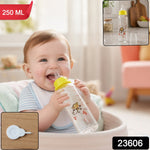A happy baby in a high chair drinks from a clear glass baby bottle with a yellow nipple and monkey design, with text