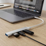 A silver Type C to four-port USB hub connected to a laptop, with a USB drive and cable