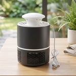 Black and white mosquito killer lamp with its USB cable on a wooden table with a folded cloth and plants.