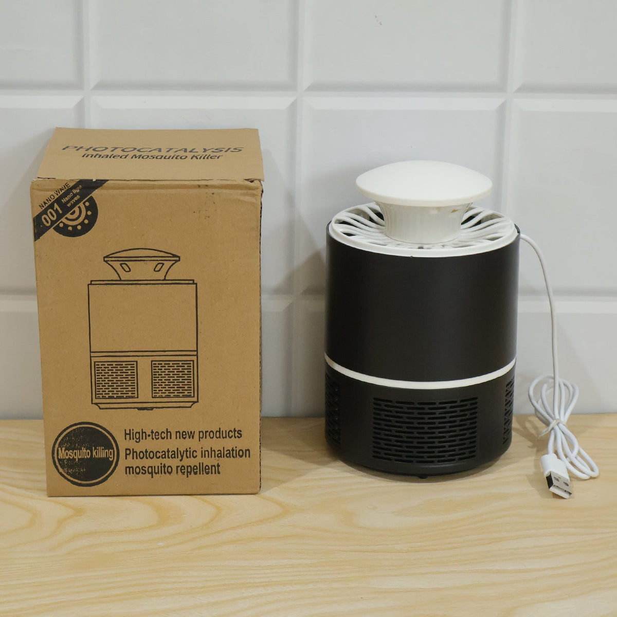 Black and white mosquito killer lamp next to its brown cardboard packaging on a wooden surface.