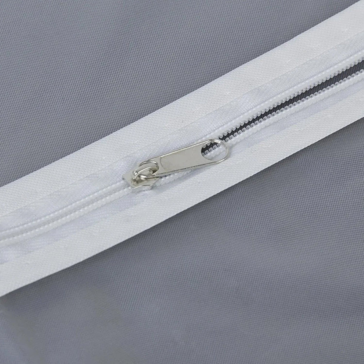A close-up view of the white zipper and silver pull on the translucent garment bag.