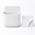 A white, empty, rounded rectangular adhesive organizer sits next to a square white adhesive pad.