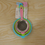 Three nested strainers with colorful plastic handles and stainless steel mesh are packaged on a wooden surface.