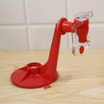 A red plastic beverage dispenser with a clear tap, resting on a light wooden surface against a white tiled wall.