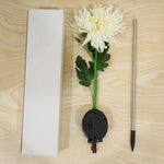 The white chrysanthemum flower solar stake light, its ground stake, and a white rectangular box laid out on a light wooden